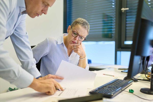 Mitarbeiter von Blank & Wilhelm besprechen gemeinsam Unterlagen im Büro
